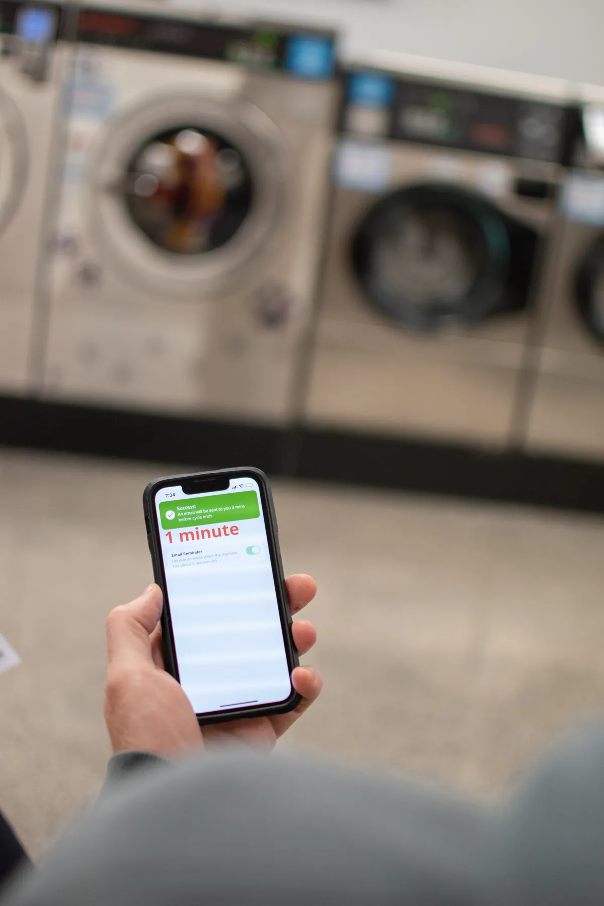 Customer checking the SpeedQueen app cycle countdown at Coast Laundromat Whangaparaoa